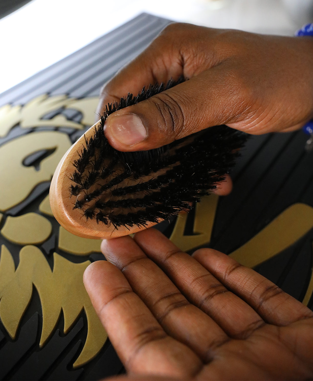 Man holding the Old Style Military Brush upside down for a closeup of the natural boar and nylon bristles over a barber counter