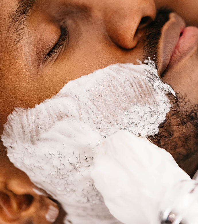 Man having Coarse Beard Shave Cream Tube applied to his face with a Professional Shave Brush by a barber