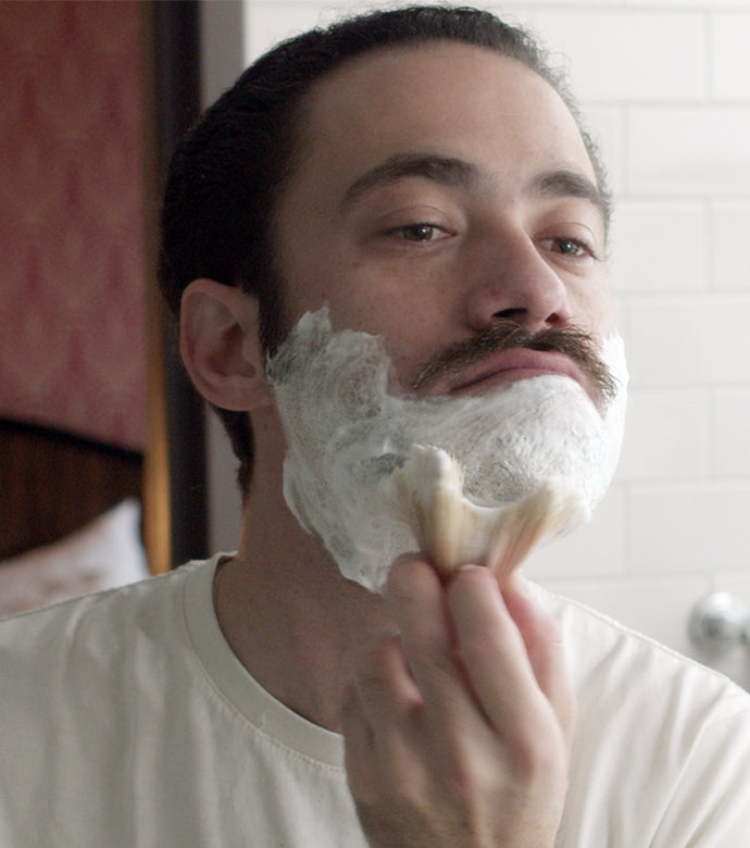 Man using Professional Shave Brush apply Shave Soap in a Bowl with a Professional Shave Brush in bathroom with a white subway tile background