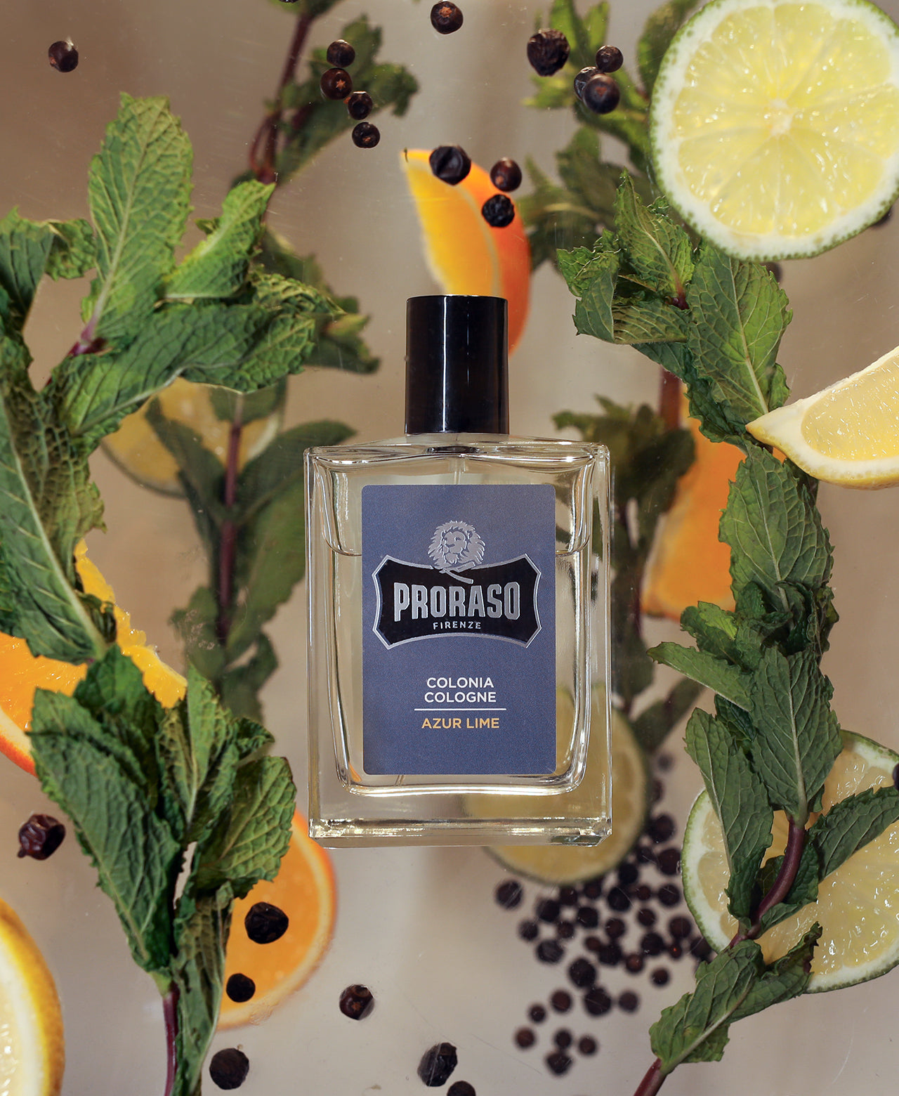Azur Lime Cologne surrounded by ingredients: Mint, Juniper Berries, Orange, Lemon