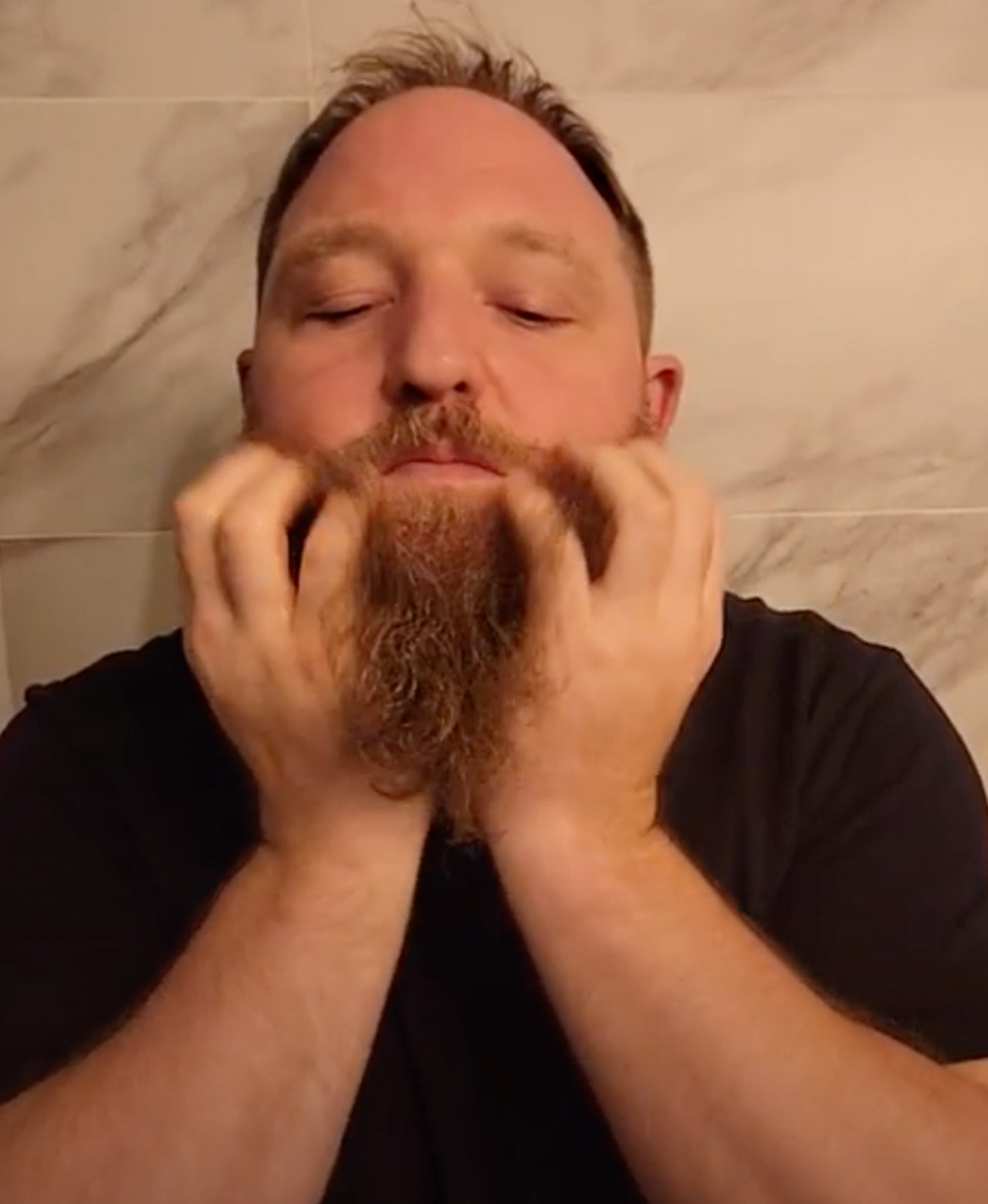 Man applying Hot Oil Beard Treatment into his long, thick beard in bathroom 