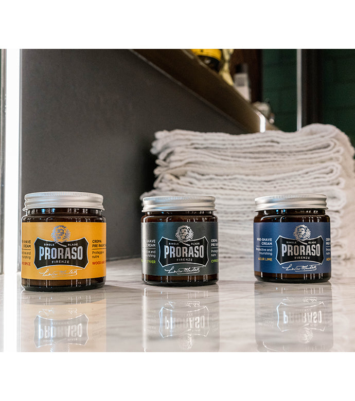 Proraso Single Blade Pre-Shave Creams in three fragrances on counter: Wood and Spice, Cypress & Vetyver and Azur Lime sitting on barber shop counter.