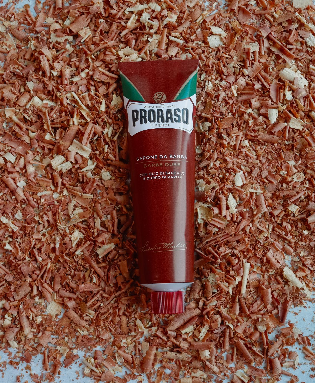 Tube of Coarse Beard Shave Cream Tube on sandalwood shavings on a grey table