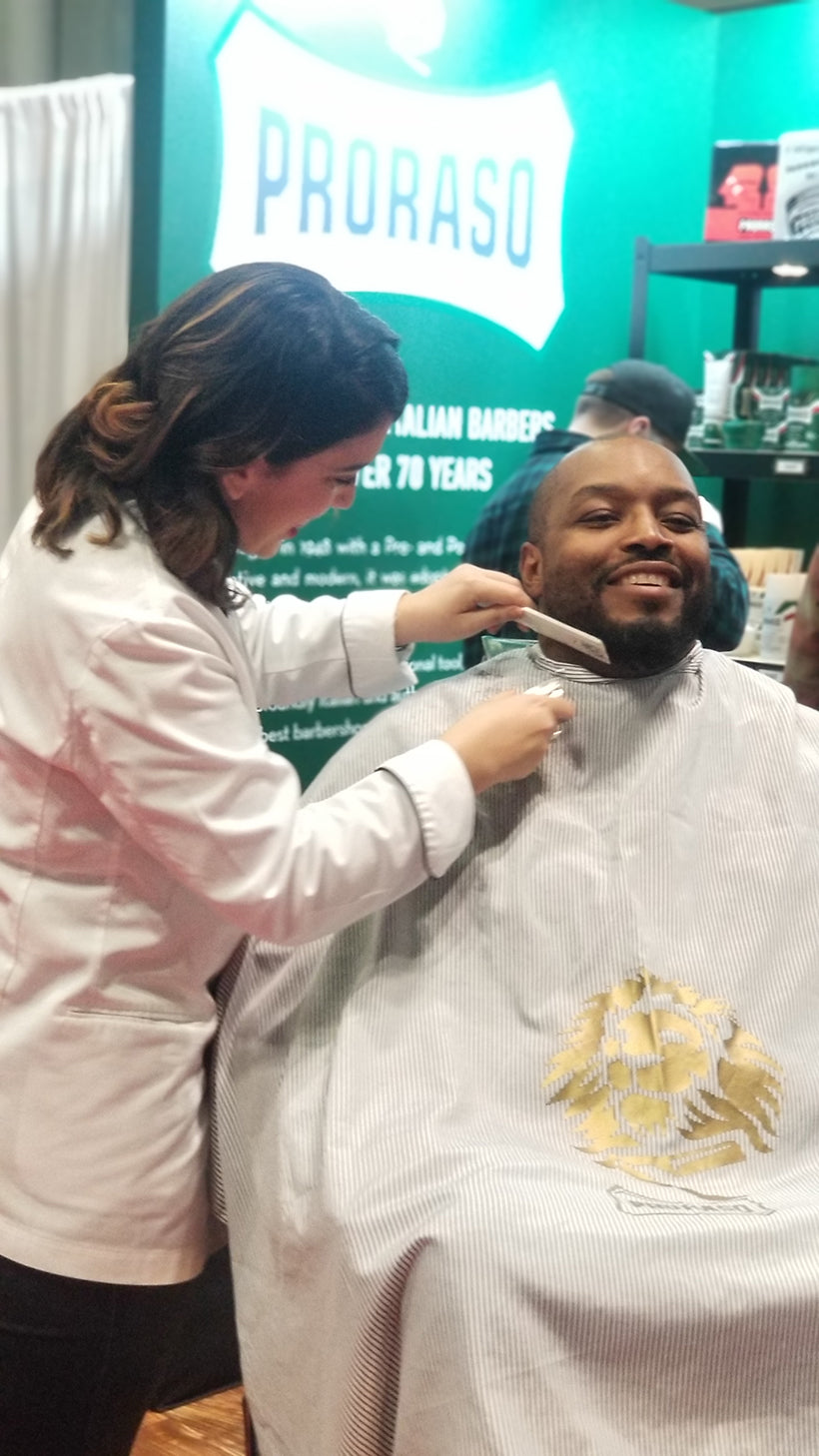 Barber combing a man's beard who is sitting in a barber chair