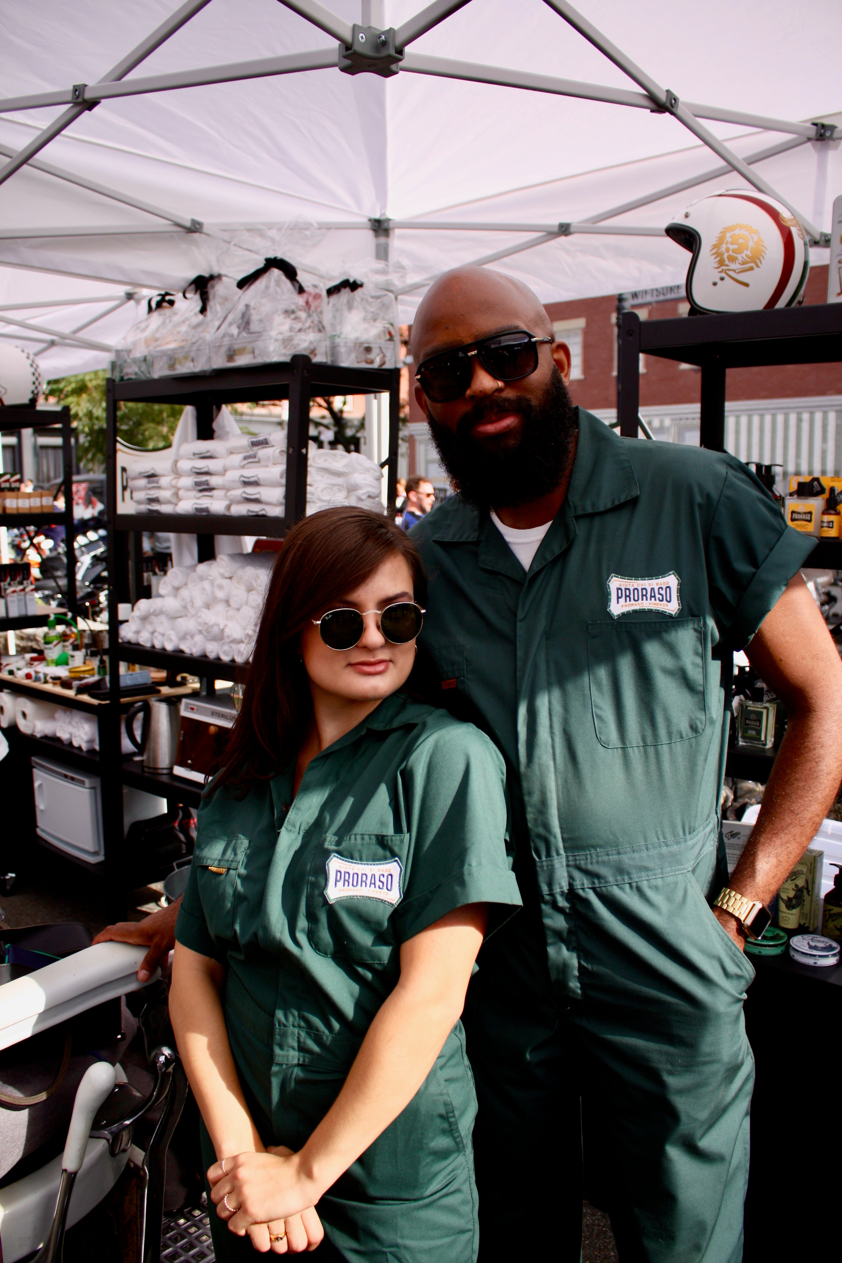 Two members of Team Proras in green jumpsuits in front of Proraso tent- a man and woman