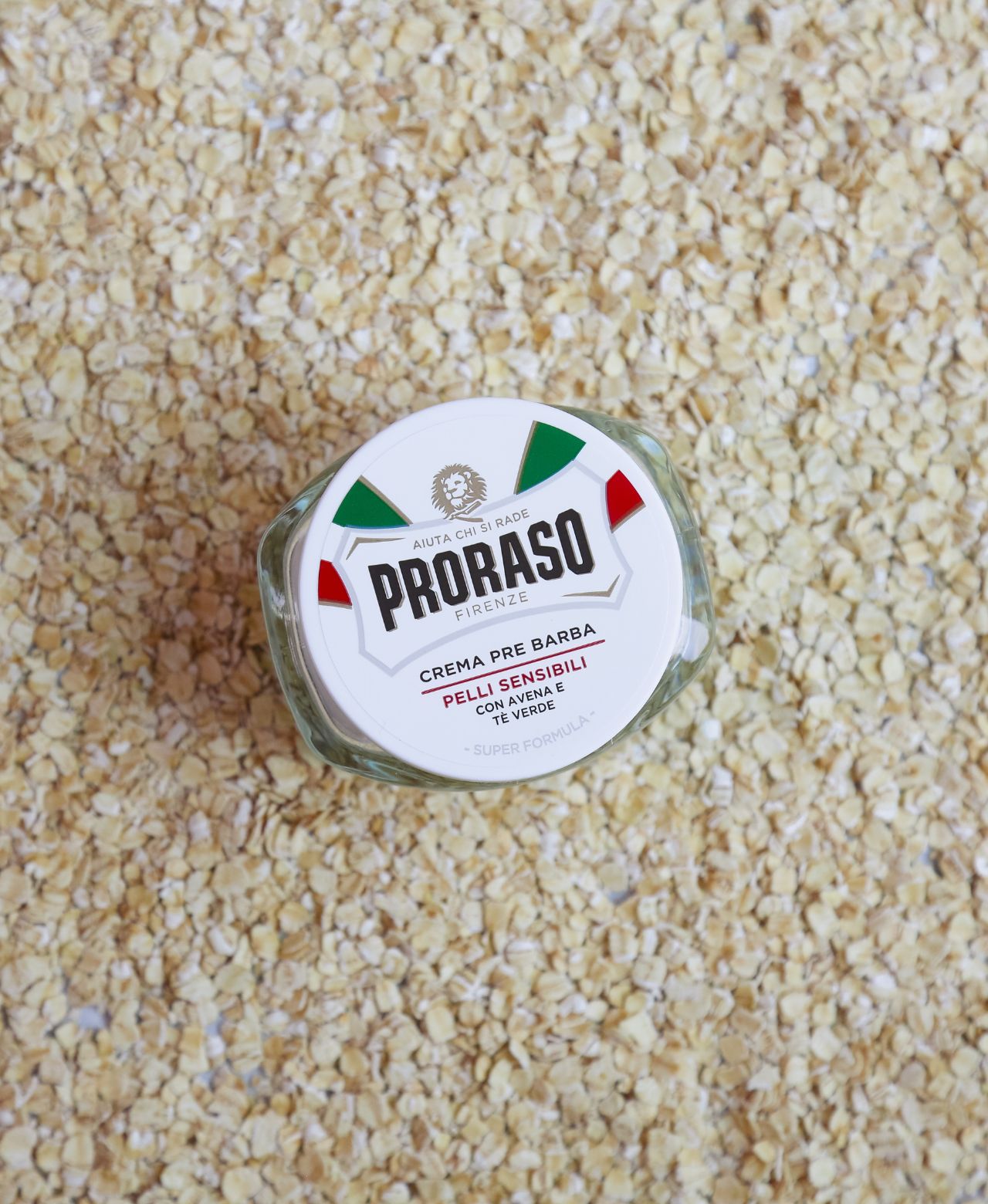 Jar of Sensitive Pre-Shave Cream sitting on oatmeal 