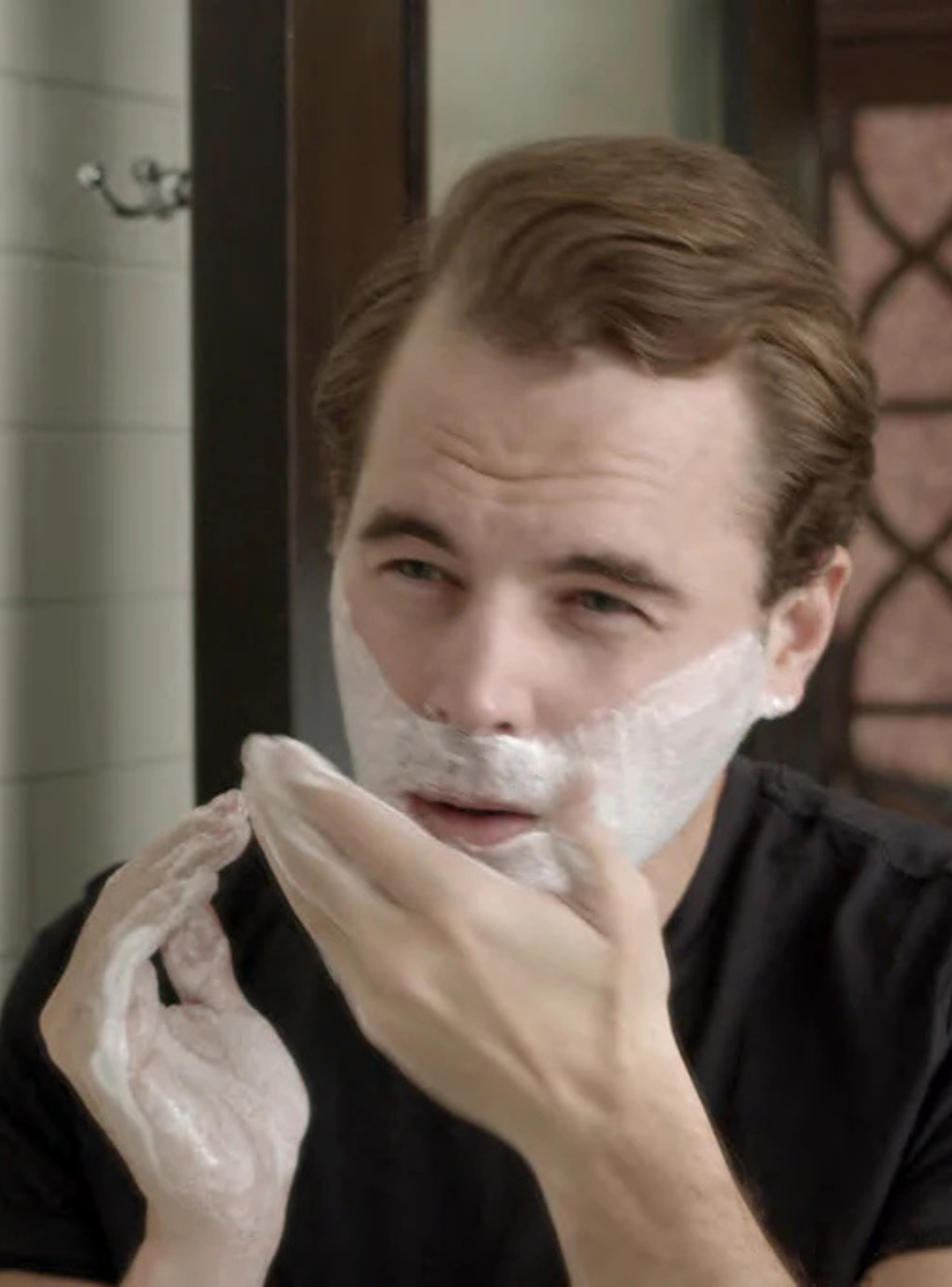 Man applying shave cream to face in bathroom getting ready to shave
