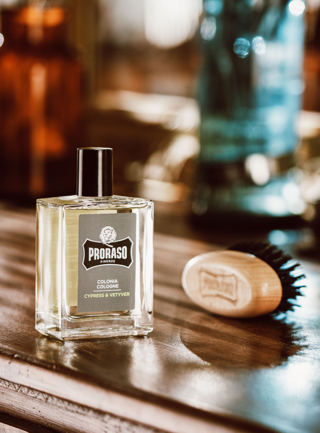 Bottle of Cypress & Vetyver Cologne with a Moustache brush sitting on a brown wooden barber station