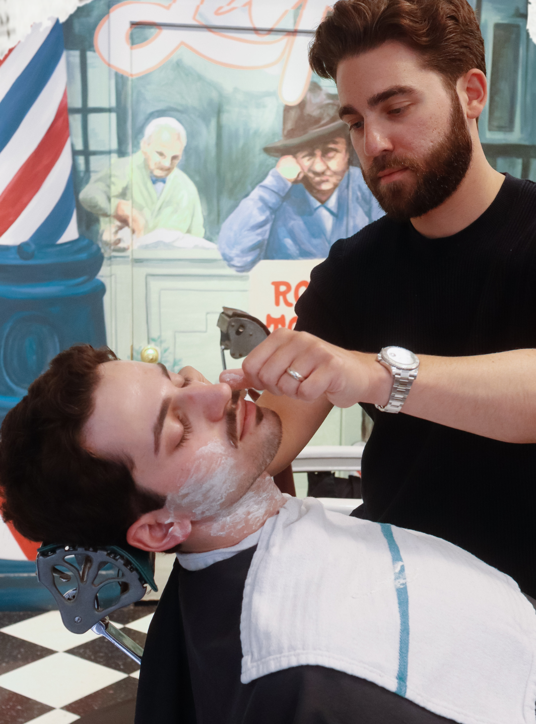 Barber Jesse Parker giving a shave to a client in his chair with shaving cream on