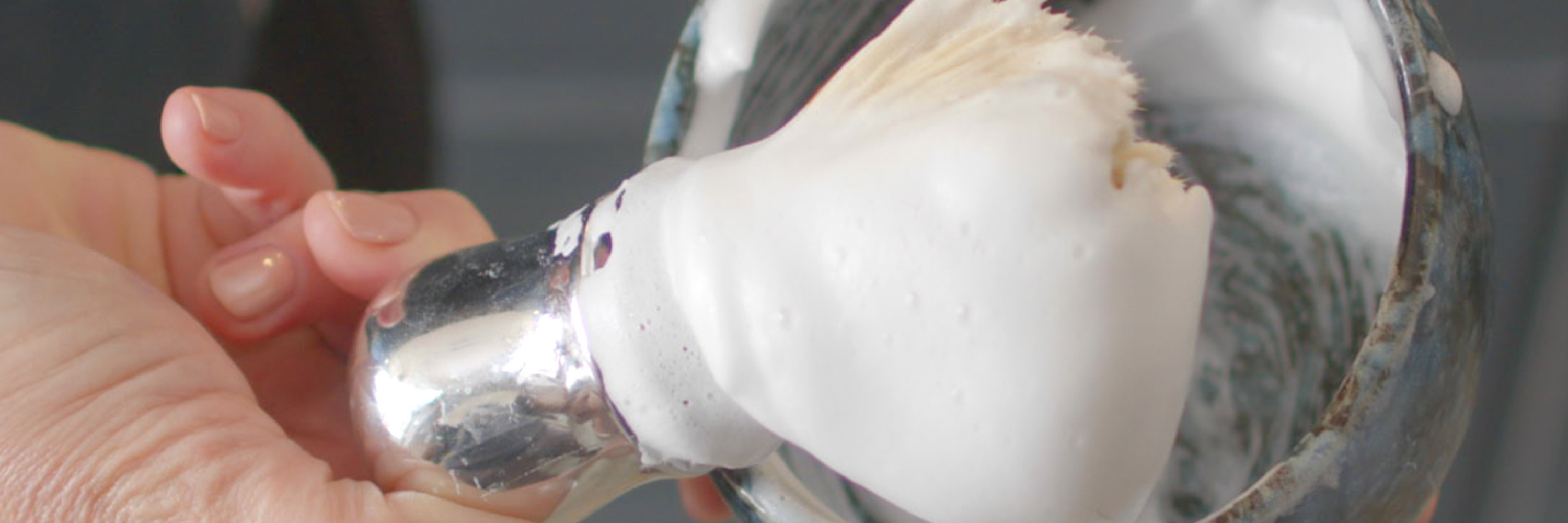 Closeup of hands building a thick lather in a black stone bowl