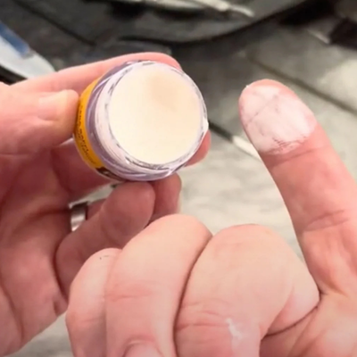 Finger scooping Moustache Wax out on finger at a barber station in front of mirror