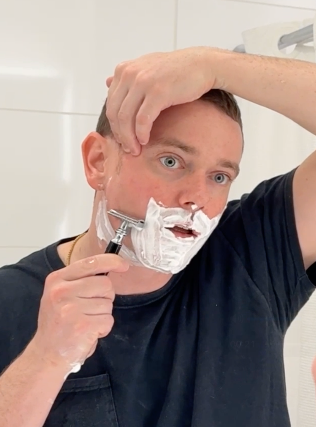Man shaving in his bathroom white white tile background