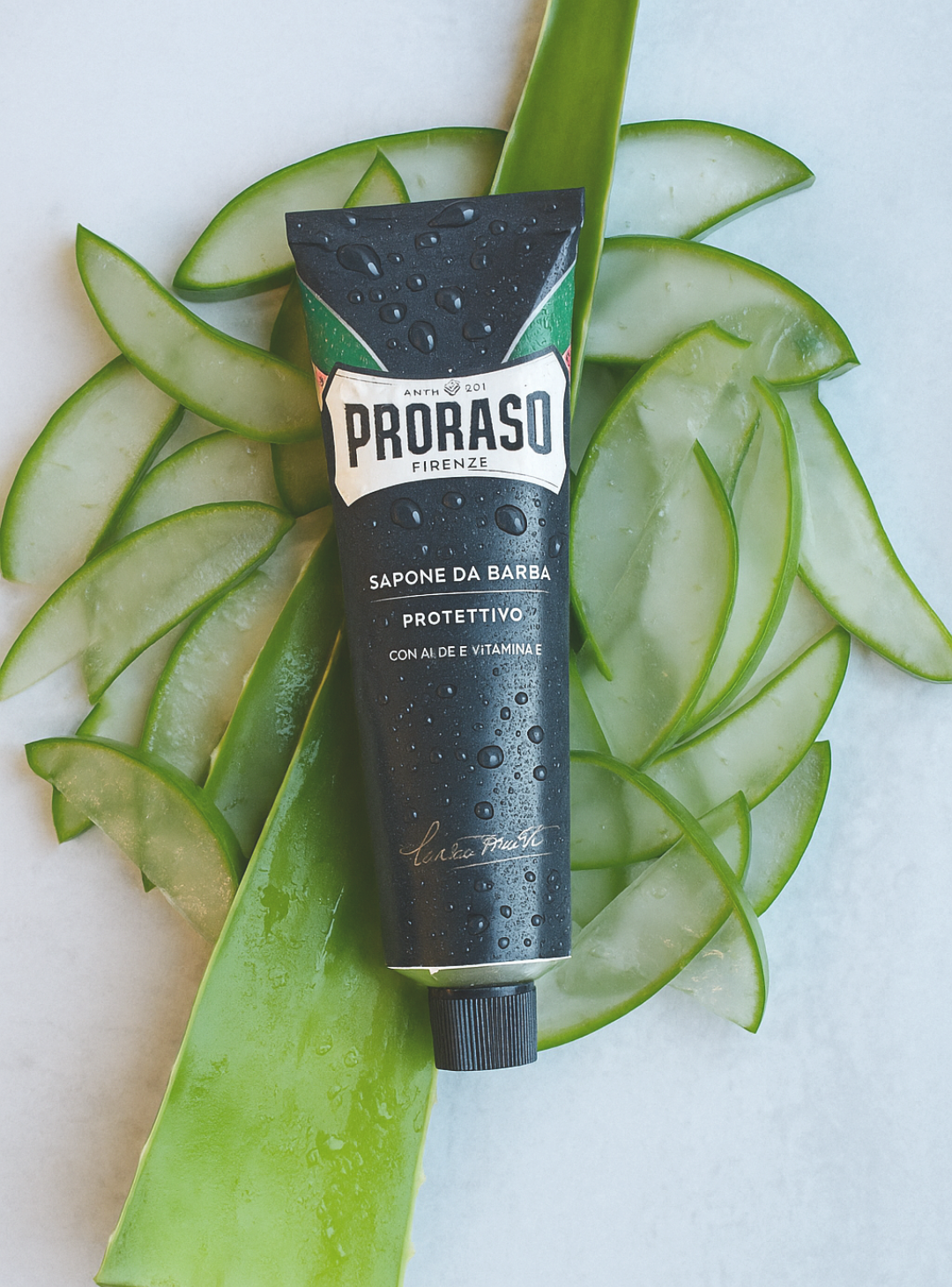 Tube of Protective Formula Shave Cream laying on top of sliced up Aloe Vera, it's main ingredient 