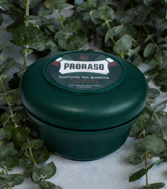 Closed jar of Refreshing Shave Soap in a Bowl sitting on blades of Eucalyptus 